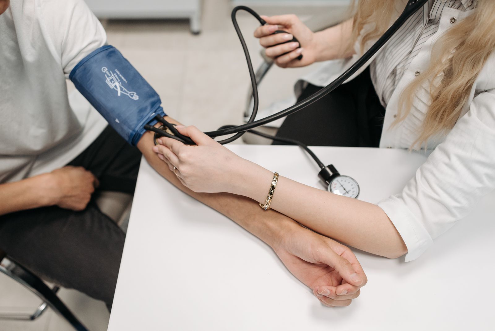 Profesional de la salud tomando la presión arterial a una paciente en consulta